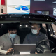 A man sits inside of a Tesla car Model 3 as a vendor talks to him at a Tesla shop inside of a shopping mall in Beijing on May 26, 2021.